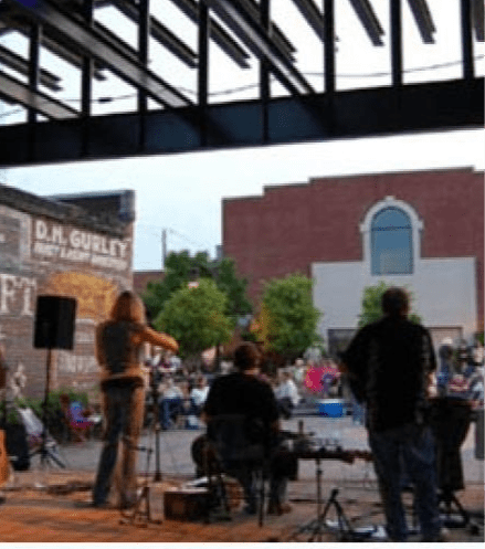 A band performing on stage outside a building with a sign that says "The Gourmet".