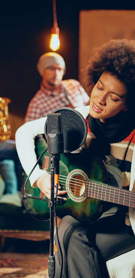 A person is playing a guitar and singing into a microphone.