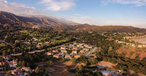 A small town is nestled in a valley with mountains in the background.