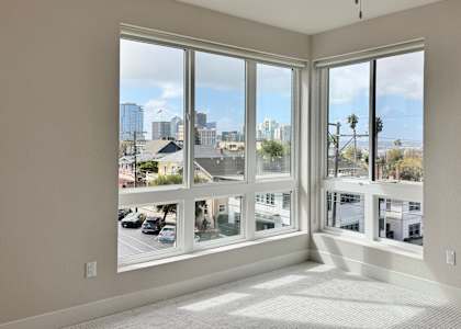A room with a ceiling fan and large windows overlooking a cityscape.