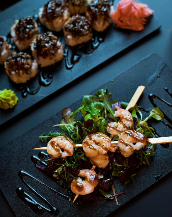 a plate of shrimp skewers and a salad on a black plate  at Sanger Place, Lorton, VA, 22079
