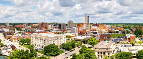 A cityscape with a mix of modern and older buildings, a prominent white building in the center, and a tall tower in the distance  at Spring Creek Townhomes, Illinois
