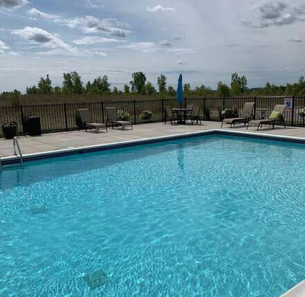 A swimming pool with a black fence and a blue umbrella at Abbey Ridge Apartment Homes, Michigan, 48371