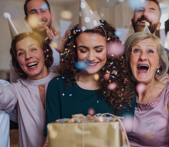 a group of people at a birthday party with birthday cake