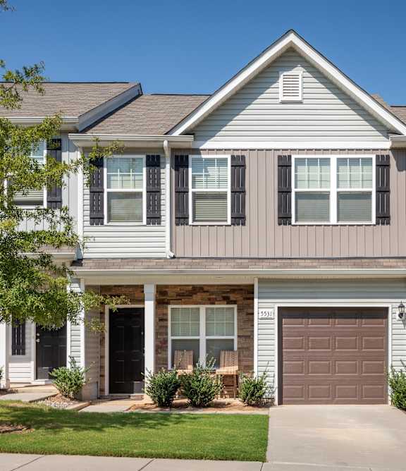 A two-story house with a garage door and a window.