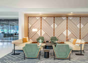 Thumbnail 5 of 24 - A modern waiting area with green and beige chairs and a wooden wall panel.