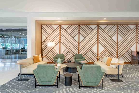 A modern waiting area with green and beige chairs and a wooden wall panel.