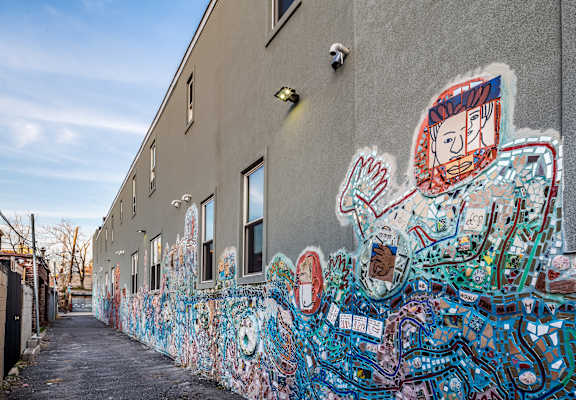 A wall covered in graffiti art with a blue sky in the background.