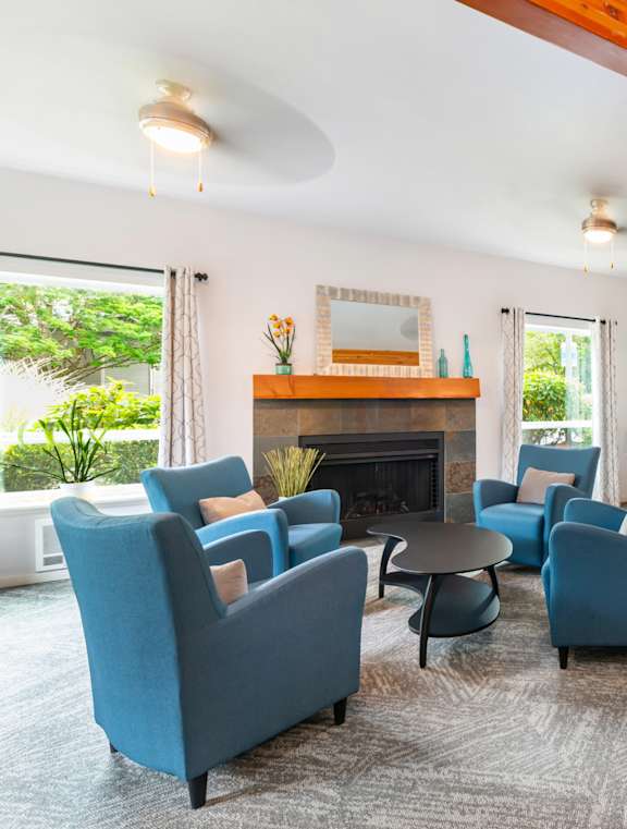 A living room with blue chairs and a fireplace.