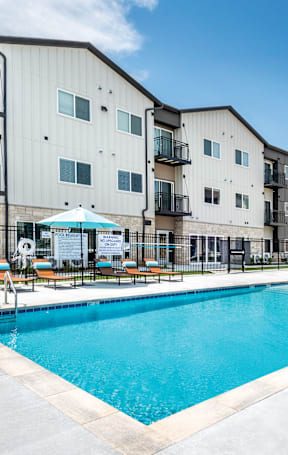 A pool in front of a building with a blue umbrella.