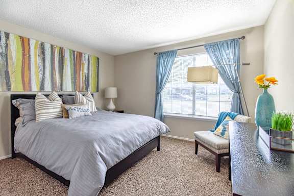 A bedroom with a large bed and a window with blue curtains.