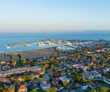 A coastal town with a pier and boats is seen from above.