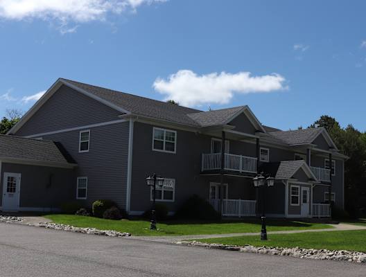 a gray house with a porch on the side of a street