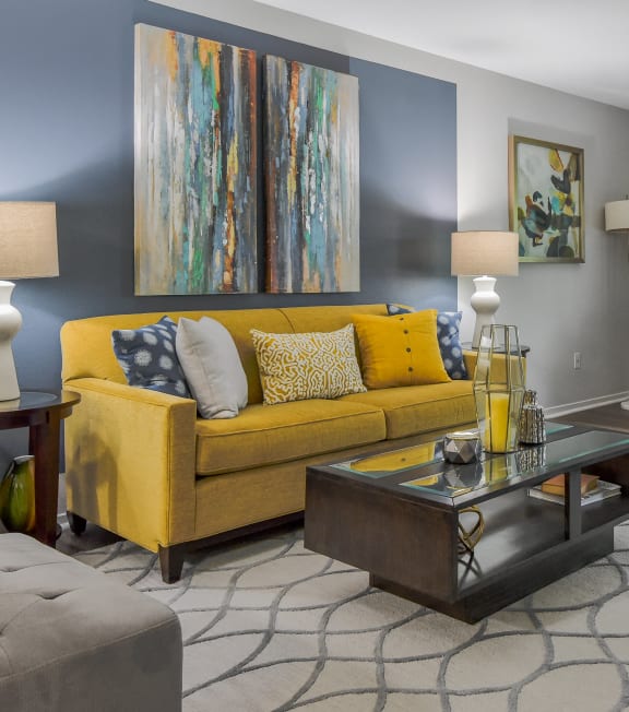 a living room with a yellow couch and a coffee table at The Villas at Main Street, Ann Arbor, Michigan