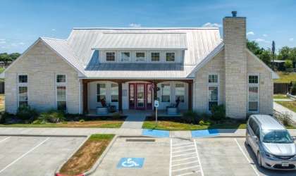 A white building with a red door and a parking lot in front.