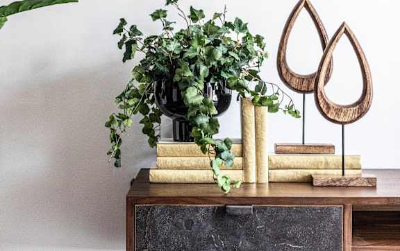 A wooden table with a potted plant and two wooden droplet shaped objects on it.