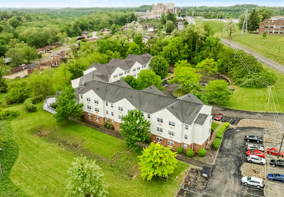 an aerial view of a white house with a gray roof and a neighborhood with trees