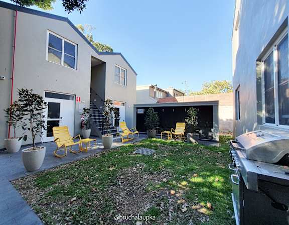 the backyard of a house with yellow chairs and a grill
