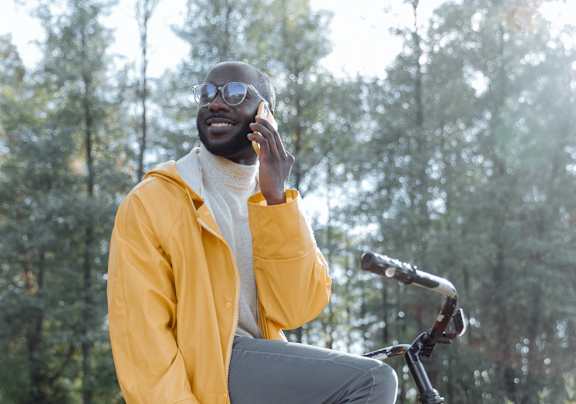 a man sitting on a bike talking on a cell phone