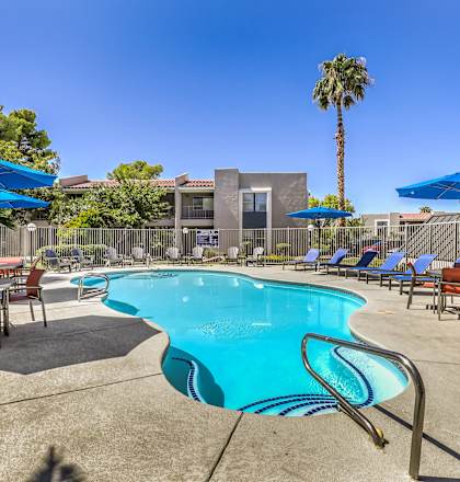 our resort style swimming pool is surrounded by patio furniture and umbrellas