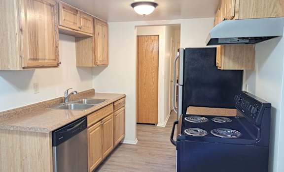 an empty kitchen with a stove refrigerator and sink