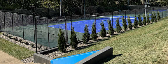 a tennis court with a fence around it and a blue pool at The Boulevard, Roeland Park, KS, 66205