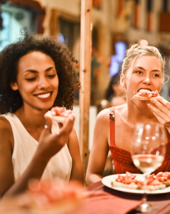two women eating pizza at a restaurant