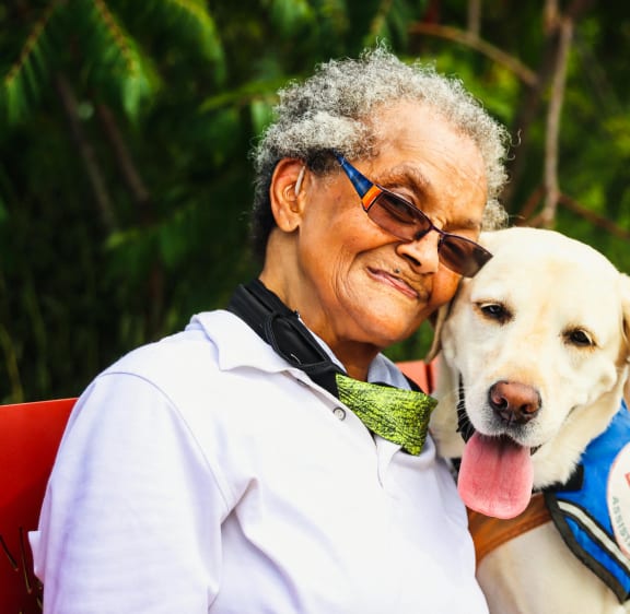an older woman sitting with a yellow dog