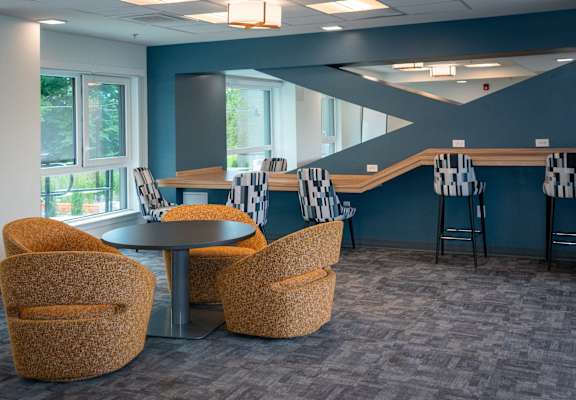 a lounge area with chairs and tables and a staircase
