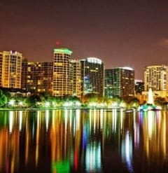 a city skyline is reflected in a lake at night at Oak Reserve at Winter Park, Florida, 32792