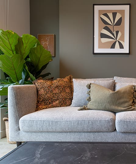 a living room with a couch with pillows and a plant