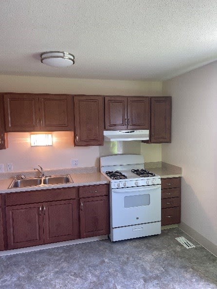 a kitchen with a white stove top oven next to a sink