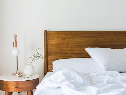 A bed with white pillows and a wooden headboard is in the image.