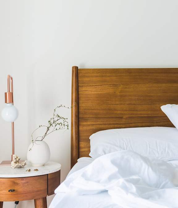 A bed with white pillows and a wooden headboard is in the image.