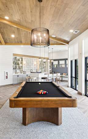 A billiard table is in the middle of a room with a fireplace and a painting on the wall.