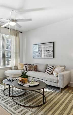A living room with a white couch, a coffee table, and a ceiling fan.
