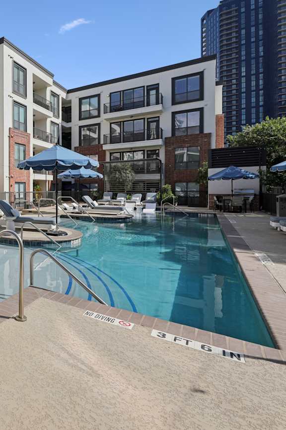 a swimming pool with orange chairs and a building in the background