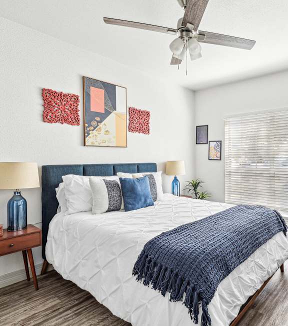 A bedroom with a bed, a ceiling fan, and a chair.