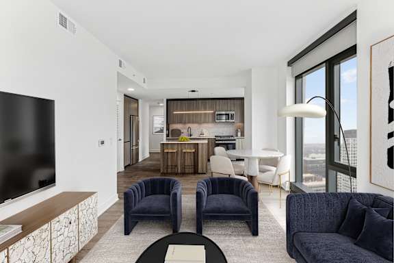 A modern living room with a television, two chairs, and a dining table.