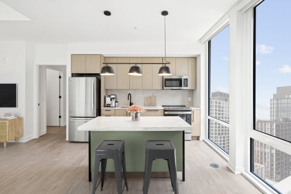 a kitchen with an island and two stools in front of a window