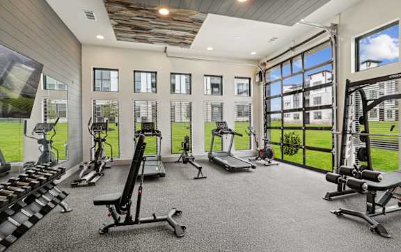 A spacious gym with a variety of equipment and a view of the outside.