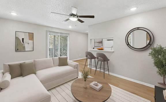 A living room with a white couch, a round table, and a ceiling fan.