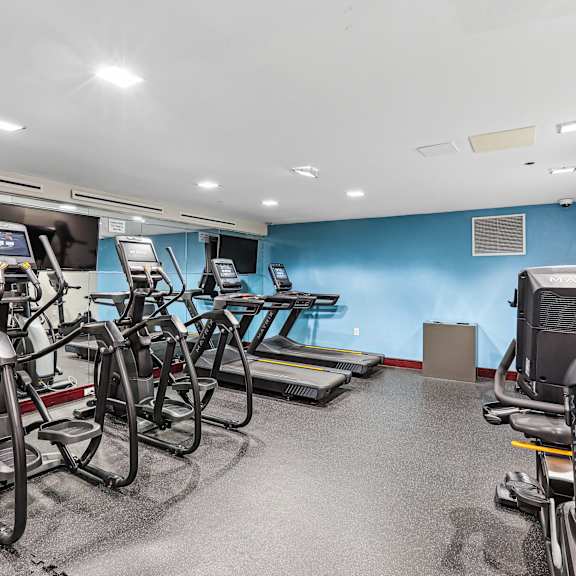 A gym with treadmills, exercise bikes, and a weight bench.