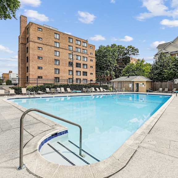 A swimming pool in front of a tall brick building.
