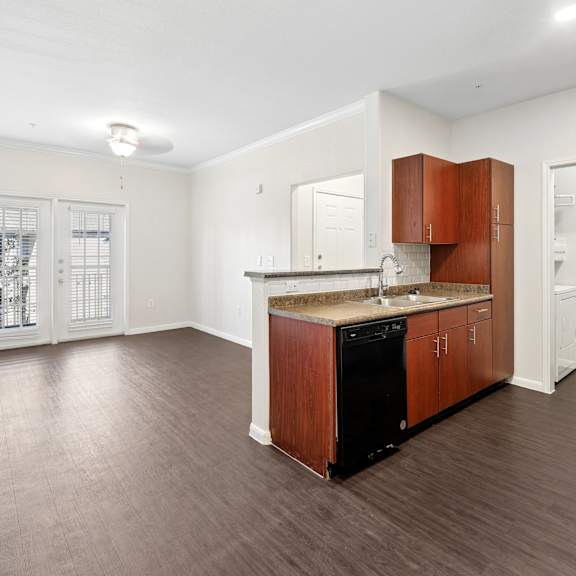 A kitchen with wooden cabinets and a black dishwasher.