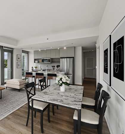 a living room with couches and a table and a kitchen with a large window