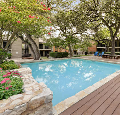 A pool surrounded by a wooden deck and trees.