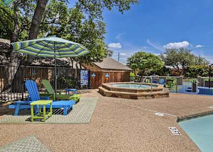 A pool area with a hot tub and chairs.