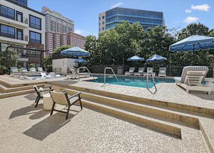 A pool area with sun loungers and umbrellas.