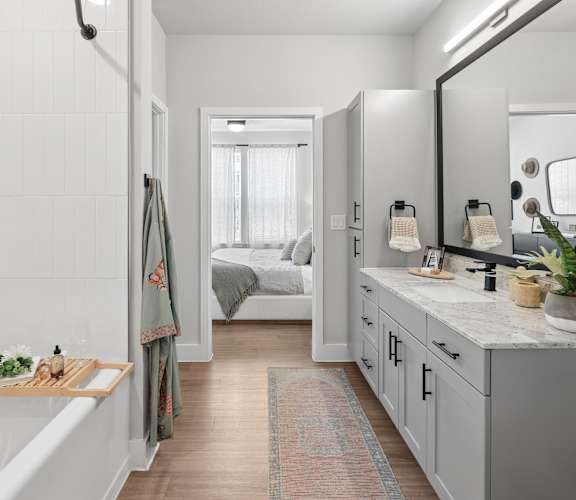 A bathroom with a white tub and a mirror.